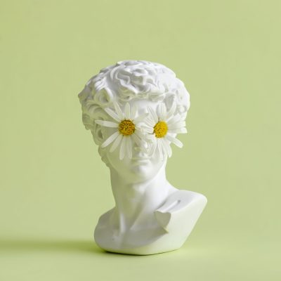 Michelangelo's David head sculpture of a chamomile flower on the eyes. Minimal pastel creative vision and look concept.